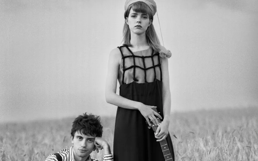 Chica y chico posan con sus guitarras en un campo