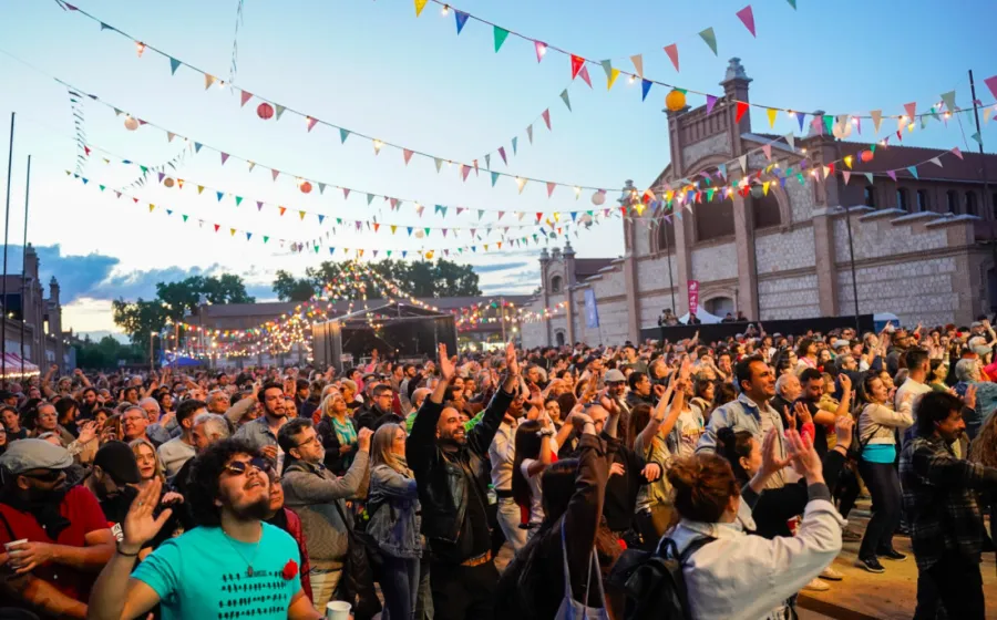 Público mira al un escenario divirtiéndose al atardecer