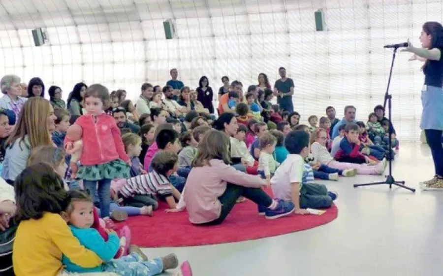 Niños sentados en el suelo atendiendo a un cuentacuentos