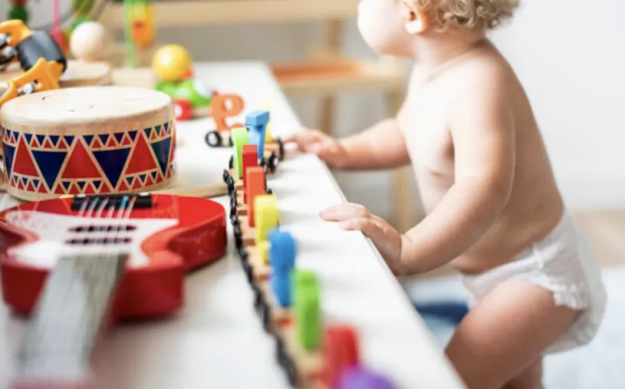 un bebé observa una mesa llena de instrumentos infantiles y juguetes