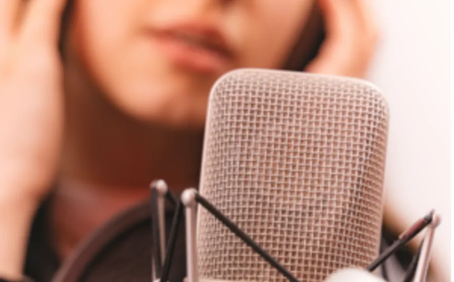 Una joven locutora con cascos delante de un micrófono
