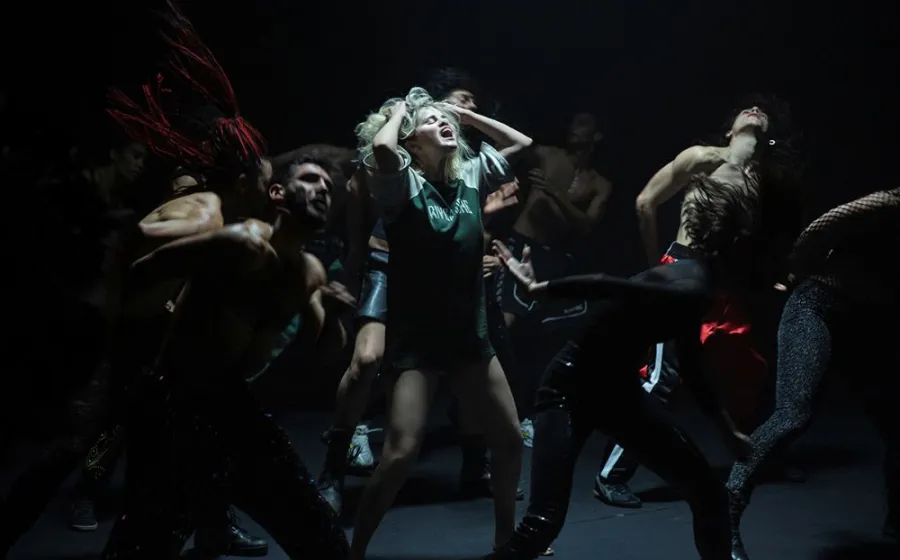 Cuerpo de baile con protagonista femenina que grita echándose las manos a la cabeza