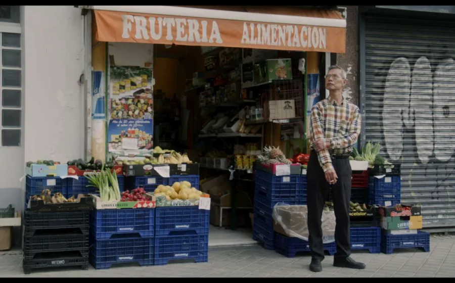 Un oriental de pie frente a una tienda de comestibles