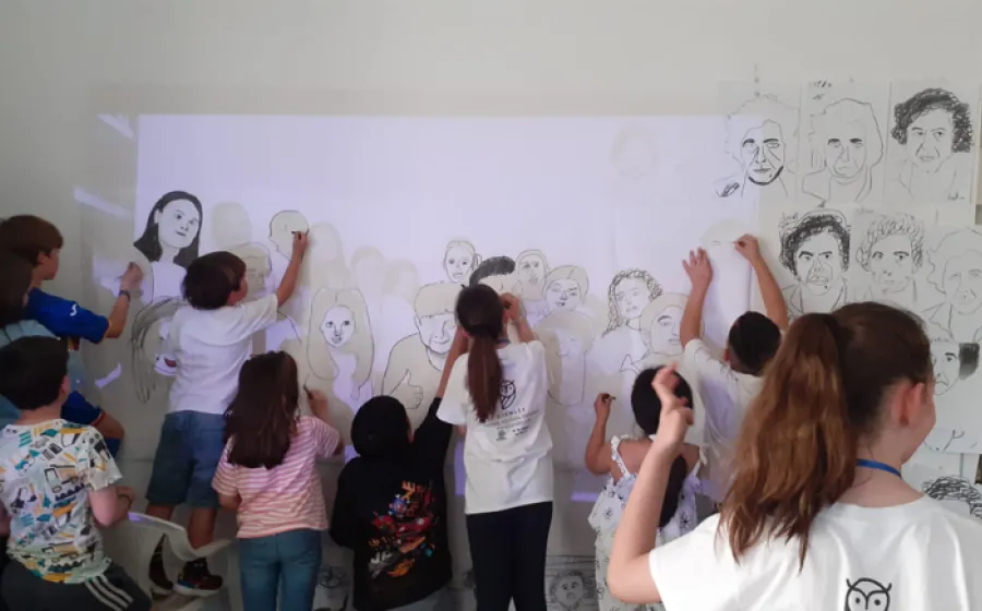 Grupo de niños pintan un panel de papel en una pared