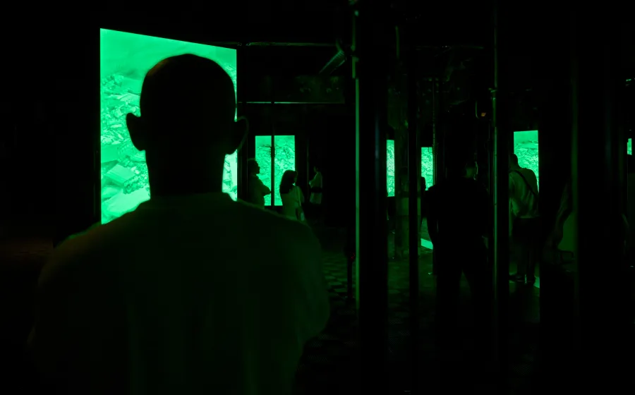 Siluetas de gente a oscuras mirando una pantalla verde