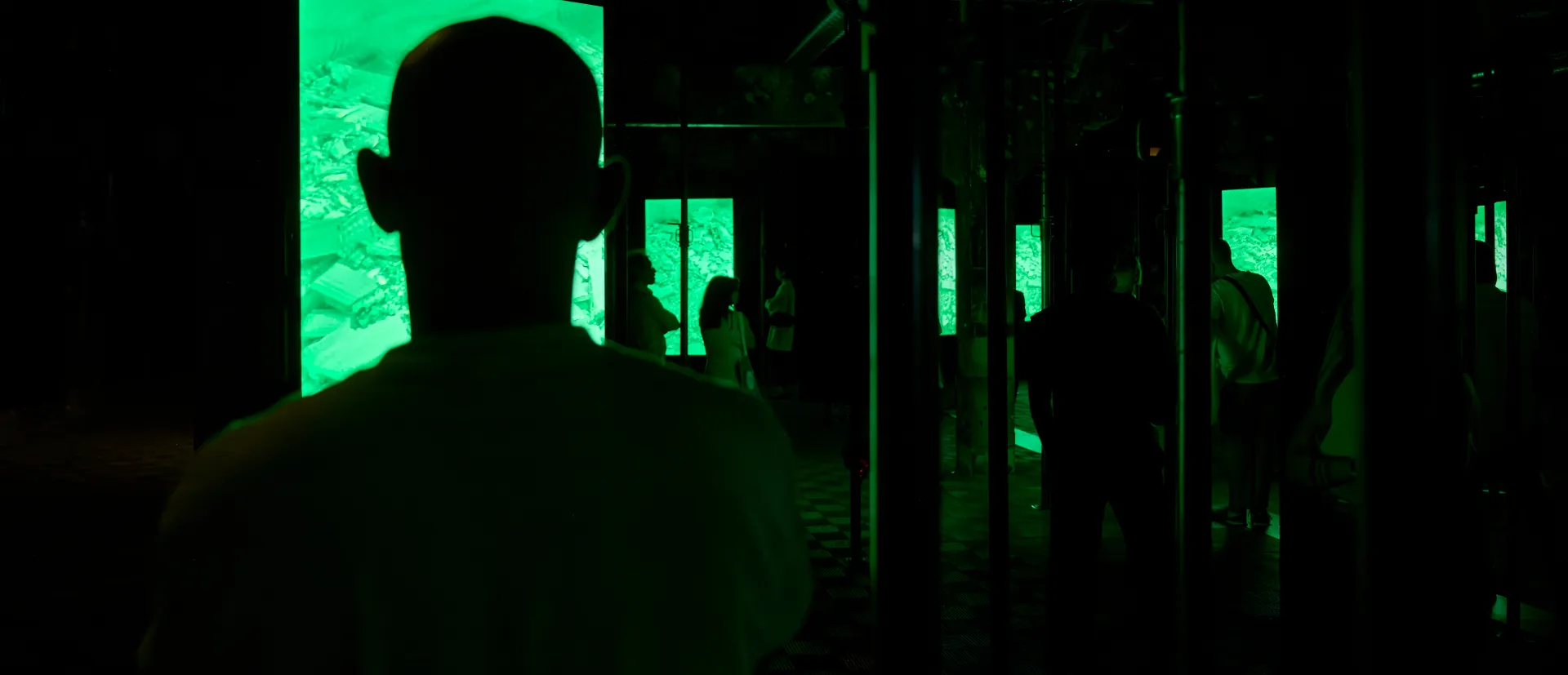 Siluetas de gente a oscuras mirando una pantalla verde