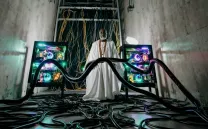 Un hombre de raza negra con toga blanca frente a unas pantallas y cables