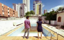 Personas observan una piscina vacía con rascacielos de fondo