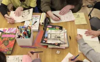 materiales de dibujo sobre una mesa y manos que lo manejan