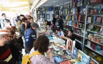 Gente mira los productos frente a un stand de librería en una feria