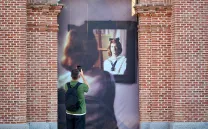 Un hombre fotografía una foto en formato grande que ocupa un vano en una pared de ladrillo