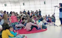 Niños sentados en el suelo atendiendo a un cuentacuentos
