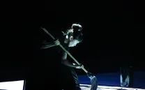 Mujer oriental con una fregona en la mano apunta al suelo bajo una luz azul