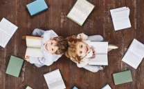 Una niña y un niño miran al techo rodeados de libro