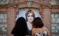 Dos personas observan una fotografía enmarcada en una fachada de ladrillo
