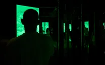 Siluetas de gente a oscuras mirando una pantalla verde