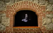 Foto de una chica cantando en blanco y negro dentro de una ventana de un edificio de ladrillo estilo neomudéjar